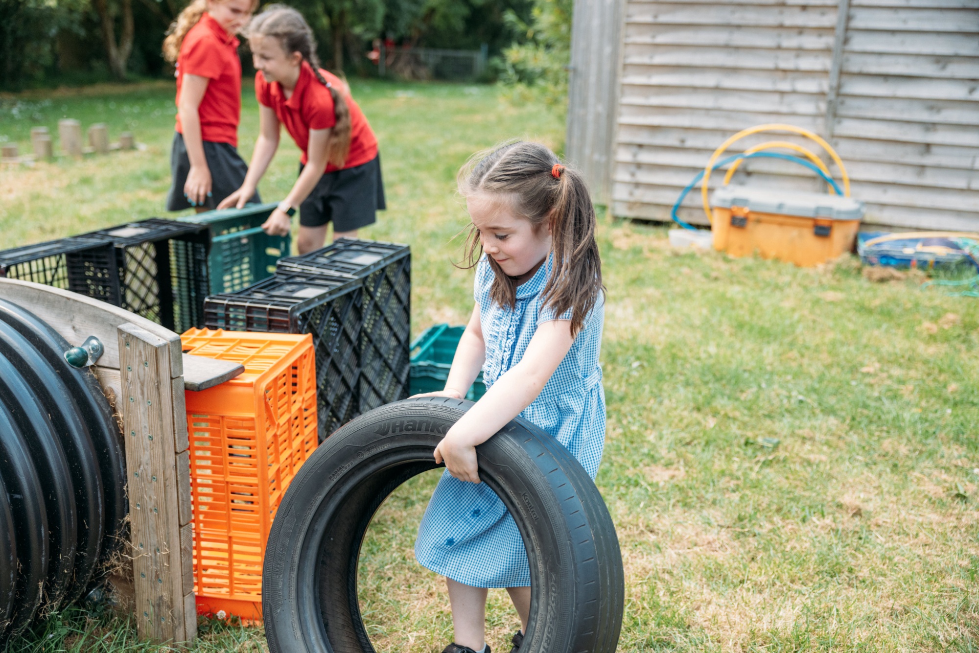 children outside playing with tyres on the grass